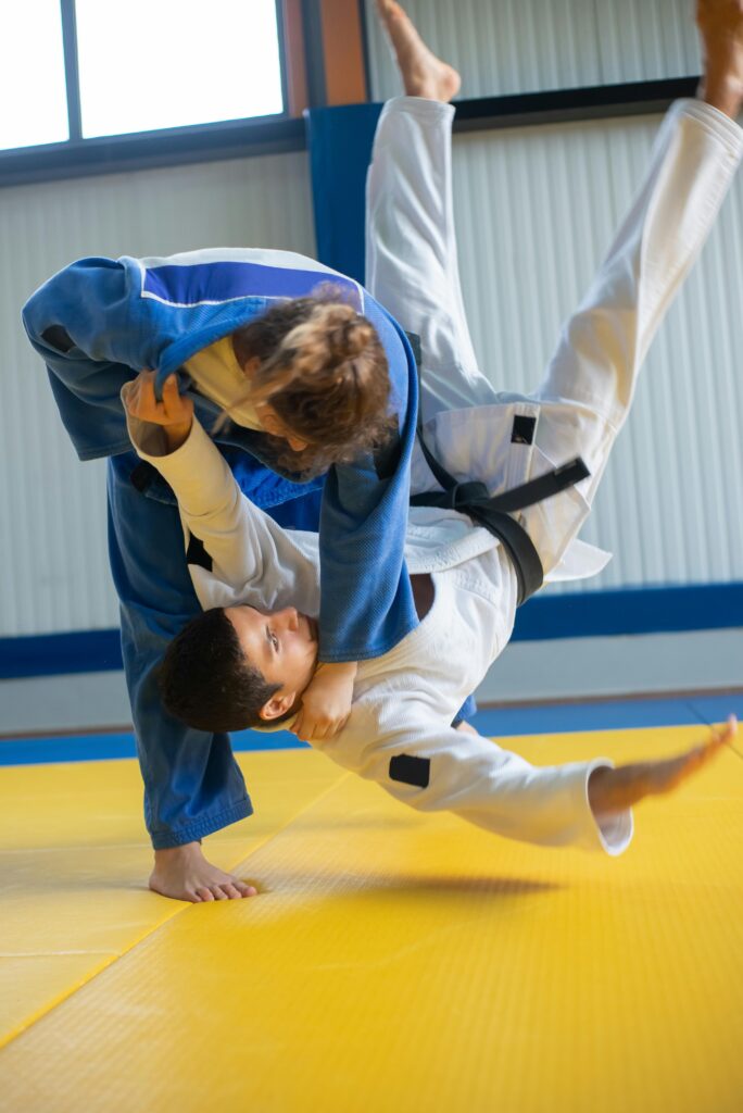 Two judokas in intense training, executing a dynamic throw on a dojo mat.
